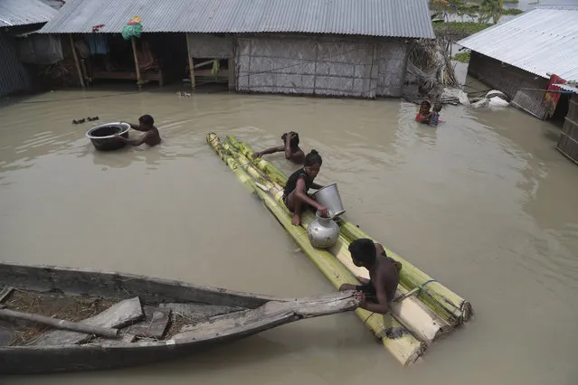 Flood affected villagers are seen near their partially submerged houses in Gagolmari village, Morigaon district, Assam, India, Tuesday, July 14, 2020. Hundreds of thousands of people have been affected by floodwaters and landslides following incessant rainfall in the region. (Photo by Anupam Nath/AP Photo)