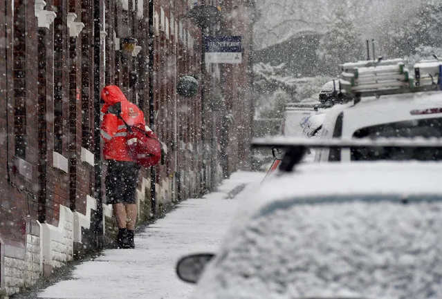 A postman delivers mail while seeming to deny the cold weather by wearing a pair of shorts, in Stalybridge, Manchester, in England, Saturday December 9, 2017. A cold front has bought snow and ice to many parts of England, with predictable disruption to the roads and some forecasters warning that communities could be cut off as temperatures plummet. (Photo by Anthony Devlin/PA Wire via AP Photo)