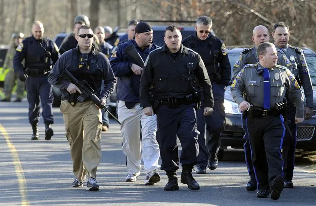 Law enforcement canvass the area following a shooting at the Sandy Hook Elementary School in Newtown, Conn., about 60 miles (96 kilometers) northeast of New York City, Friday, December 14, 2012. An official with knowledge of Friday's shooting said 27 people were dead, including 18 children. (Photo by Jessica Hill/AP Photo)