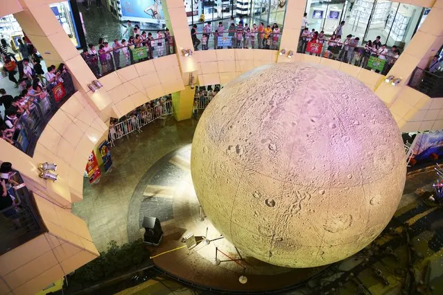 Customers look at a 10-metre-tall installation in the shape of the moon, to celebrate the Mid-Autumn Festival, at a department store in Nanjing, Jiangsu province, China, September 26, 2015. The Mid-Autumn Festival is celebrated on the 15th day of the eighth month in the lunar calendar during a full moon, which falls on September 27 this year. (Photo by Reuters/Stringer)