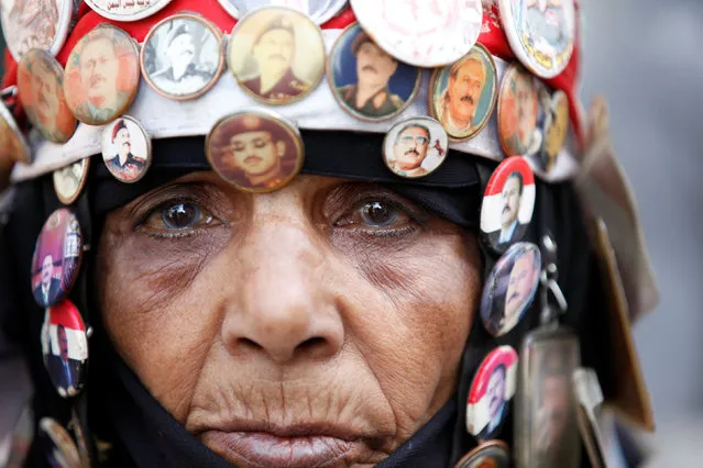A woman wearing souvenirs with photos of Yemen's former president Ali Abdullah Saleh and his eldest son Ahmed waits outside a parliament session held for the first time since a civil war began almost two years ago, in Sanaa, Yemen August 13, 2016. (Photo by Khaled Abdullah/Reuters)