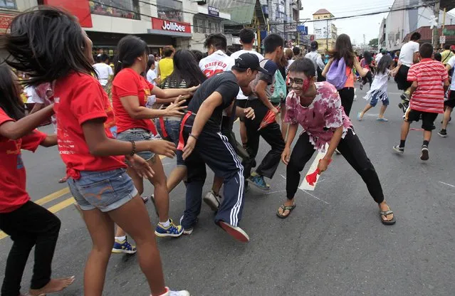 A man wearing a zombie costume chases participants during a Zombie Run held as part of Halloween celebrations in Marikina city, east of Manila October 30, 2014. (Photo by Romeo Ranoco/Reuters)