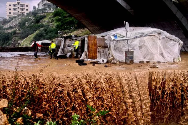 Rescue workers help a family evacuate a flooded area in Jadra, south of Beirut, Lebanon, January 7, 2013. The country has been hit with a snow storm that has blocked roads in the mountains and brought heavy rains to the capitol. (Photo by Mohammed Zaatari/Associated Press)