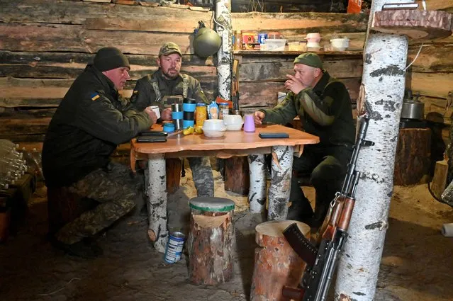 Soldier of the National Guard of Ukraine share their tea in a dugout in the northern occupied territories of Kharkiv region on October 21, 2022, amid the Russian military invasion of Ukraine. (Photo by Sergey Bobok/AFP Photo)