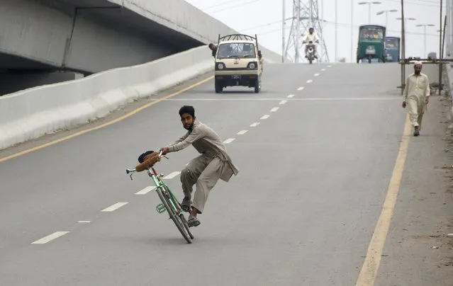 A man does tricks on his bicycle on a highway as the Eid holiday begins in Peshawar, Pakistan September 23, 2015. (Photo by Khuram Parvez/Reuters)