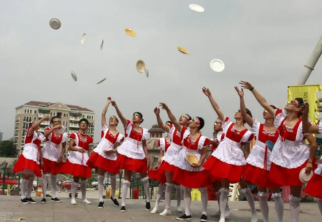 Male staff members of an amusement park wearing maid costumes throw chinaware into the air to be smashed during an event promoting their stress-release activities to mark World Mental Health Day, in Hangzhou, Zhejiang province, China, October 9, 2015. (Photo by Reuters/China Daily)
