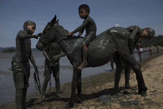 Kids cover a horse with mud as they take part in the traditional “Bloco da Lama” or “Mud Block” carnival party in Paraty, Brazil, Saturday, February 10, 2018. (Photo by Leo Correa/AP Photo)