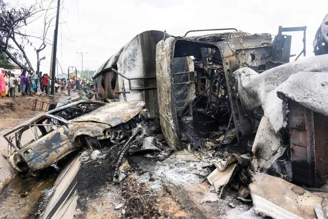 Bystanders look on at the wreckage of a truck that caught fire in Lokoja, Nigeria, on September 23, 2020. At least nine people, including several students, were killed when a truck carrying petrol overturned and caught fire on a busy road in central Nigeria on Wednesday The accident happened at Lokoja, the capital of Kogi state, after the truck's brakes failed and its driver lost control. (Photo by Haruna Yahaya/AFP Photo)