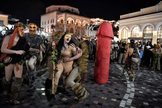 People dressed as the Greek mythological figures dance around a sculpture of a large phallus during a reenactment of an ancient celebration dedicated to the Greek god Dionysus, marking the carnival season, on February 11, 2018, in Athens, Greece. (Photo by Louisa Gouliamaki/AFP Photo)