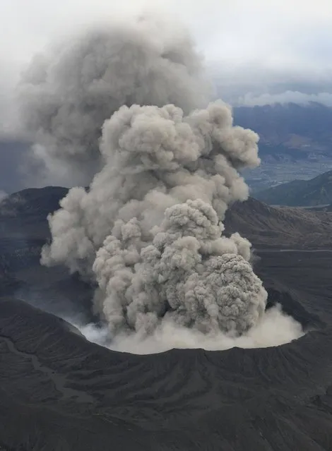 In this November 26, 2014 photo, volcanic smoke billows from Mount Aso, Kumamoto prefecture, on the southern Japanese main island of Kyushu. The volcano is blasting out chunks of magma in the first such eruption in 22 years, causing flight cancellations and prompting warnings to stay away from its crater. (Photo by AP Photo/Kyodo News)
