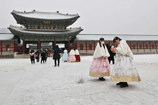 People wearing traditional hanbok dress walk through Gyeongbokgung Palace during snowfall in Seoul on January 26, 2023. (Photo by Jung Yeon-je/AFP Photo)