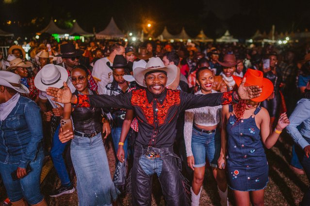 Sheriff Knight (C), the dancing Cowboy, leads the line dance during the International Cowboy Day at Ngong race course in Nairobi on July 26, 2025. Country music have a loyal fan base in Kenya and the popularity of the music continuing to grow, the event was celebrated by hundreds of attendees with a collective of country artists performing. The headline of the event was Sir Elvis, Kenya's biggest country star. (Photo by Fredrik Lerneryd/AFP Photo)