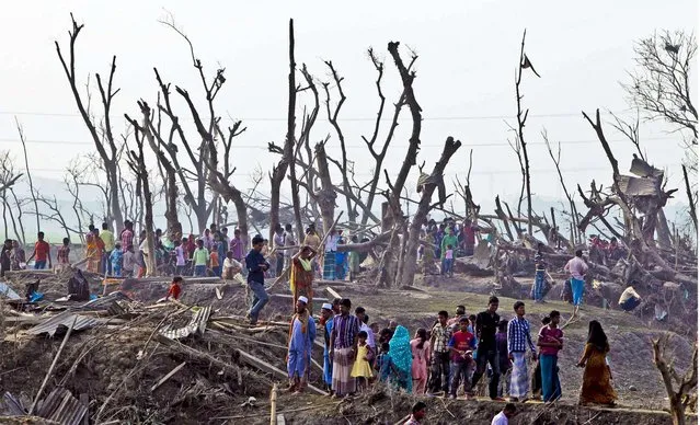 People wonder throught an are hit by a tornado in Bangladesh, on March 23, 2013. The tornado ripped through 20 villages in eastern Bangladesh, killing almost two dozen of people and  injured 200 hurt. (Photo by A.M. Ahad/Associated Press)