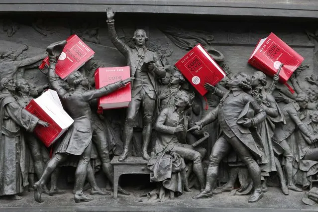 Copies of the French Civil Code are placed amongst a frieze depicting the “Oath of the Jeu de Paume” (June 20, 1789) on the Republic statue as French lawyers, notaries and bailiffs attend a national protest against a government reform plan to deregulate their profession in Paris December 10, 2014. (Photo by Charles Platiau/Reuters)