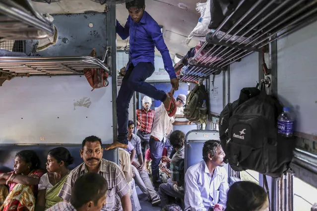 A passenger climbs on a seat and luggage racks on the Kalka Mail train awhile traveling from Fatehpur station to Allahabad Junction station near Fatehpur, Uttar Pradesh, India, on Tuesday, September 29, 2015. The 162-year-old system is Asia's oldest. It is the nation's economic artery, employer of more than 1.3 million people, and the government's most intractable problem. (Photo by Dhiraj Singh/Bloomberg)