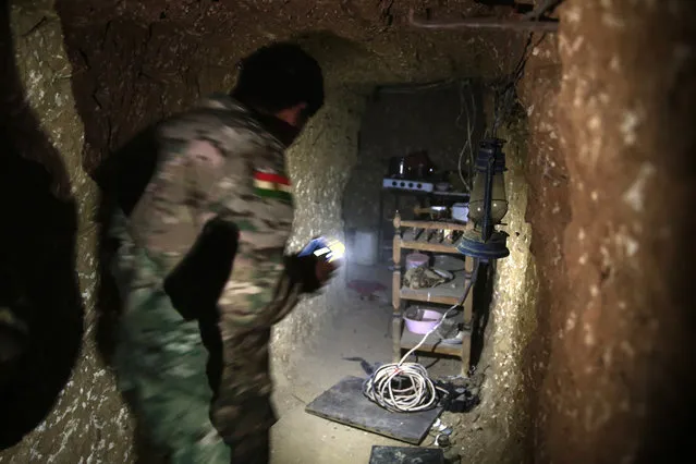 A peshmerga fighter walks through the kitchen of an underground tunnel made by Islamic State fighters, Tuesday, October 18, 2016. The Kurdish forces found the tunnel in the town of Badana that was liberated from the Islamic State group on Monday. The fighters built tunnels under residential areas so they could move without being seen from above to avoid airstrikes. (Photo by Bram Janssen/AP Photo)