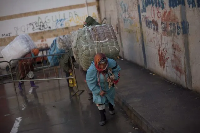 Women porters carry bundles on their backs for transport across the El Tarajal boarder separating Morocco and Spain's North African enclave of Ceuta, in Ceuta on December 4, 2014. (Photo by Jorge Guerrero/AFP Photo)