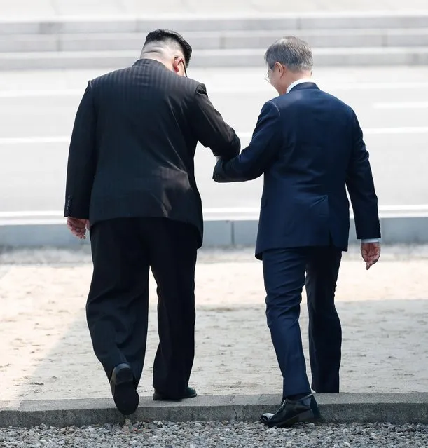 South Korean President Moon Jae-in (R) and North Korean leader Kim Jong-un (L) hold hands as they cross the military demarcation line (MDL) at the Joint Security Area (JSA) on the Demilitarized Zone (DMZ) in the border village of Panmunjom in Paju, South Korea, 27 April 2018. South Korean President Moon Jae-in and North Korean leader Kim Jong-un are meeting at the Peace House in Panmunjom for an inter-Korean summit. The event marks the first time a North Korean leader has crossed the border into South Korea sine the end of hostilities during the Korean War. (Photo by EPA/EFE/Korea Summit Press Pool)