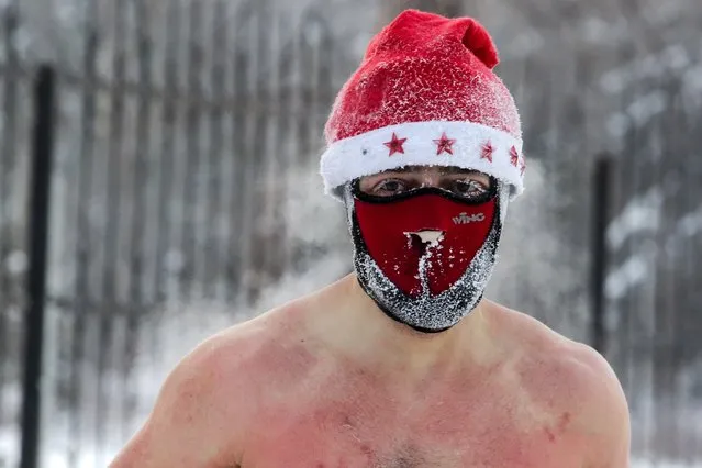 A member of the ice swimming club, wearing christmas face mask and hat, prepares to go swimming into the icy water as the temperature dropped down to minus 34 degrees celsius, in the Siberian city of Novosibirsk, on December 26, 2020. (Photo by Rostislav Netisov/AFP Photo)