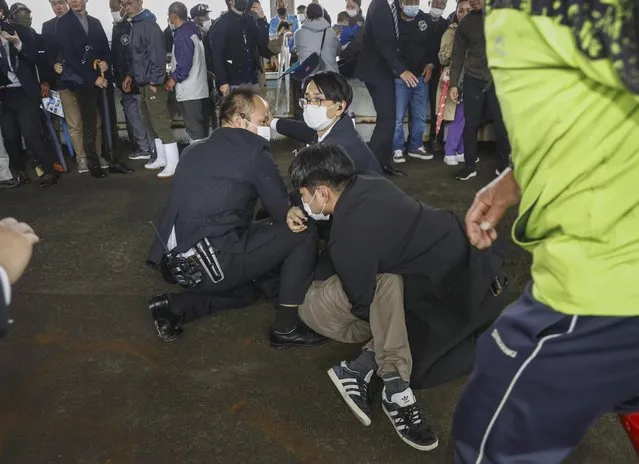 A man, on the ground, who threw what appeared to be a smoke bomb, is caught at a port in Wakayama, western Japan Saturday, April 15, 2023. Japan’s NHK television reported Saturday that a loud explosion occurred at the western Japanese port during Prime Minister Fumio Kishida’s visit, but there were no injuries. (Photo by Kyodo News via AP Photo)