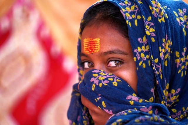 A girl waits for a devotee to apply a tilak on her forehead during the annual Jhiri Fair at Kanachack village on the outskirts of Jammu, India, Wednesday, November 5, 2025. (Photo by Channi Anand/AP Photo)
