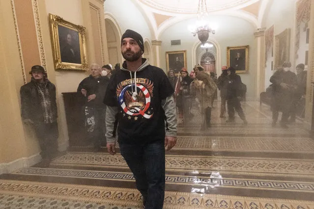 Smoke fills the walkway outside the Senate Chamber as supporters of President Donald Trump are confronted by U.S. Capitol Police officers inside the Capitol, Wednesday, January 6, 2021 in Washington. (Photo by Manuel Balce Ceneta/AP Photo)