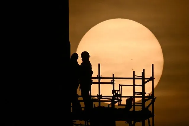 Workers prepare the SpaceX Starship as the sun sets behind them ahead of the launch from the SpaceX Starbase in Boca Chica, Texas on April 18, 2023. SpaceX has rescheduled for April 20, 2023, the first test flight of Starship, the most powerful rocket ever built, designed to send astronauts to the Moon, Mars and beyond, after a technical glitch forced a halt to the countdown. (Photo by Patrick T. Fallon/AFP Photo)
