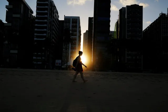  A woman walks on the beach as the sun sets between buildings in Recife June 10, 2014. (Photo by Brian Snyder/Reuters)