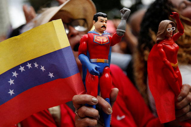 A supporter of Venezuela's President Nicolas Maduro holds an action figure of “Super Bigote” (Super Mustache), a superhero inspired by the Venezuelan President, as people attend a ceremony hosted by Maduro at Miraflores Palace to swear in new community-based organisations, as U.S. President Donald Trump's administration ramps up pressure on Maduro's government, in Caracas, Venezuela, on December 1, 2025. (Photo by Leonardo Fernandez Viloria/Reuters)