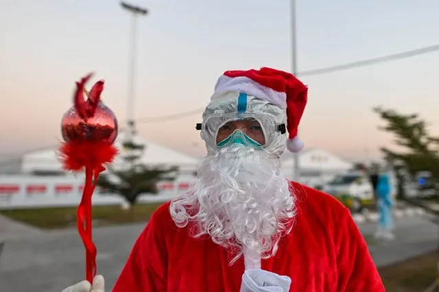 A healthcare worker dressed as Santa Claus prepares to distribute gifts to children at the Ayeyarwady Covid Centre in Mandalay, Myanmar, on December 25, 2020, Christmas Day, amid the Covid-19 pandemic, caused by the novel coronavirus. (Photo by Ye Aung Thu/AFP Photo)