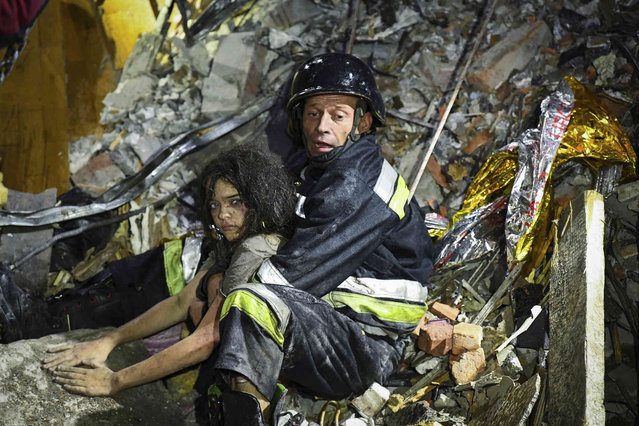 In this photo provided by the National Police of Ukraine on September 3, 2024, a rescue worker pulls out from under the rubble an injured girl at a hotel damaged by a Russian strike in Zaporizhzhia, Ukraine. (Photo by National Police of Ukraine via AP Photo)