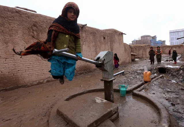 An Afghan woman fills containers with water near her temporary shelter at an internally displaced person's (IDP) camp on the outskirts of Herat, Afghanistan, January 21, 2015. Dozens of families are living in temporary shelters even in harsh winters and most depend on aid distributions by the United Nations High Commissioner for Refugees (UNHCR). (Photo by Jalil Rezayee/EPA)