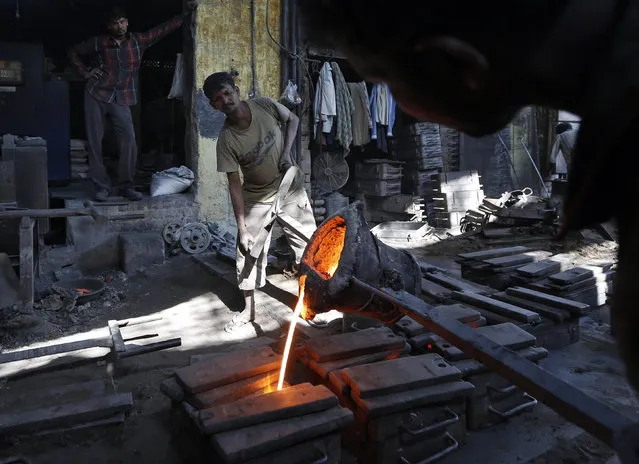 Workers pour molten iron from a ladle to make spare parts used in textile looms inside an iron casting factory in Ahmedabad, India, December 11, 2015. India's annual industrial output grew 9.8 percent in October, its fastest pace in five years, government data showed on Friday. (Photo by Amit Dave/Reuters)