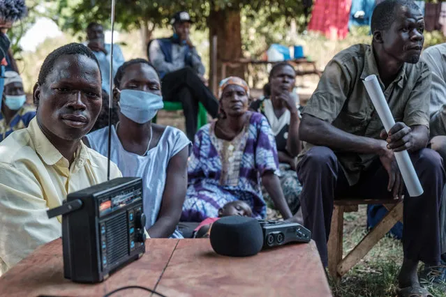 Mohammed Olanyia (L) who lost his whole family in 2004 in the Lukodi massacre, listens to the radio with his neighbours in Lukodi, Uganda, on February 2021 during the verdict given by the International Criminal Court (ICC) on Dominic Ongwen. The International Criminal Court in The Hague, Netherlands, on February 4, 2021 convicted Dominic Ongwen, a Ugandan child soldier-turned-Lord's Resistance Army commander, of war crimes and crimes against humanity. (Photo by Sumy Sadurni/AFP Photo)