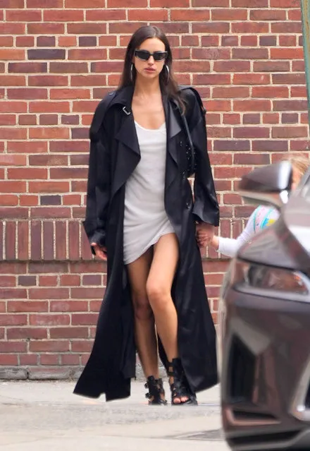 Irina Shayk is pictured out with her daughter in New York City on June 12, 2023. The Russian supermodel wore a black trench coat, white slip dress, and gladiator style sandals. (Photo by The Image Direct)