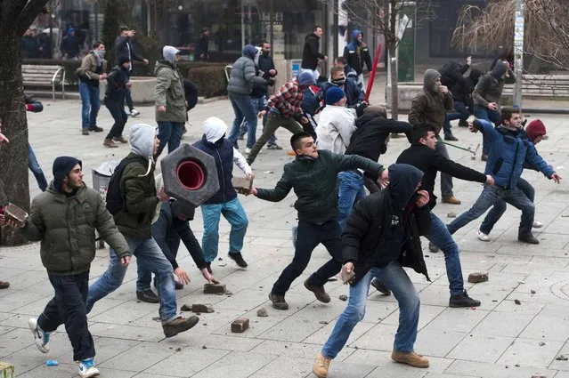 Protestors throw bricks and stones as they clash with riot police during a demonstration in Pristina on January 27, 2015. Several people were injured, including at least four police officers, when Kosovo police clashed with thousands of violent protesters demanding the dismissal of a Serb minister accused of insulting the ethnic-Albanian majority. (Photo by Armend Nimani/AFP Photo)