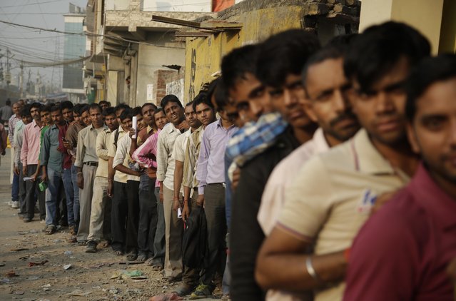 Indians stand in a queue to deposit and exchange discontinued currency notes, outside a bank in New Delhi, India, Sunday, November 13, 2016. Chaotic scenes played out across India over the weekend, with long lines growing even longer and scuffles breaking out, as millions of anxious people tried to change old currency notes that became worthless days earlier when the government demonetized high-value bills. (Photo by Altaf Qadri/AP Photo)