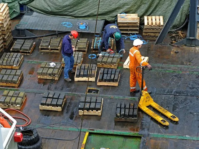 Picture issued by Odessy Marine of the Odyssey Marine Exploration crew inspecting the silver bars as they are recovered from the the SS Gairsoppa site, on July 23, 2013. Odyssey Marine Exploration recovered 61 tons of bullion this month, 1574 precious bars, from the SS Gairsoppa, a 412 foot (126 metres) British cargo ship that went down in February 1941 about 300 miles off Ireland in international waters. (Photo by Odessy Marine/PA Wire)