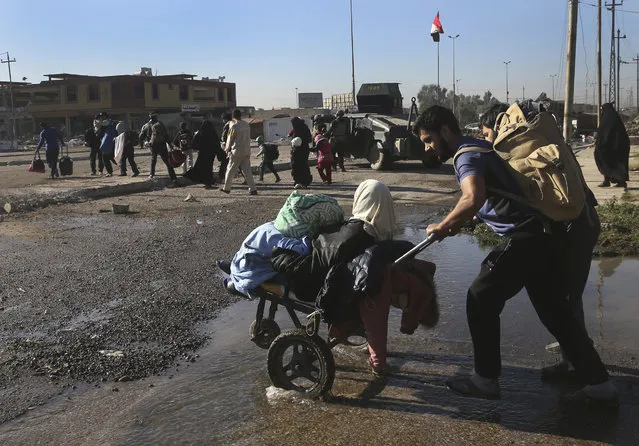 Iraqi citizens fleeing the fighting between Iraqi forces and Islamic State militants, as they cross one of al-Tahrir front line neighborhood, in Mosul city, Iraq, Sunday, November 20, 2016. A top Iraqi commander said on Sunday that troops were continuing to advance toward the center of Mosul, pushing back Islamic State fighters, but hindered by sniper fire and suicide bombings as well as concern over the safety of civilians. (Photo by Hussein Malla/AP Photo)