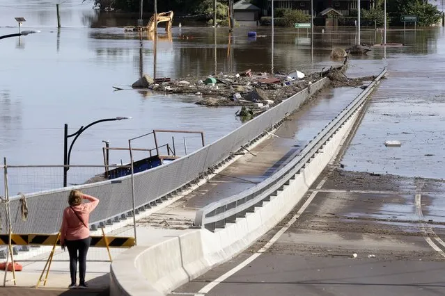 A woman looks at debris caught on a submerged bridge in Windsor, northwest of Sydney, Australia, Thursday, March 25, 2021. Emergency services have made hundreds of rescues since the flooding began last week and insurance companies expect the damage in New South Wales to exceed 1 billion Australian dollars ($760 million). (Photo by Rick Rycroft/AP Photo)