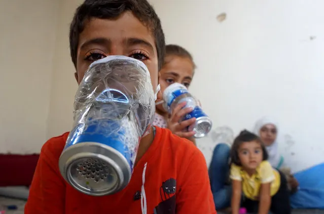 Children try improvised gas masks in their home in Binnish in Syria's rebel-held northern Idlib province as part of preparations for any upcoming raids on September 12, 2018. The Syrian regime and its Russian ally are threatening an offensive to retake the northwestern province of Idlib, Syria's last rebel bastion. (Photo by Muhammad Haj Kadour/AFP Photo)