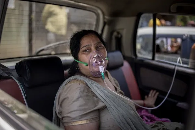 A COVID-19 patient sits inside a car and breathes with the help of oxygen provided by a Gurdwara, a Sikh house of worship, in New Delhi, India, Saturday, April 24, 2021. (Photo by Altaf Qadri/AP Photo)