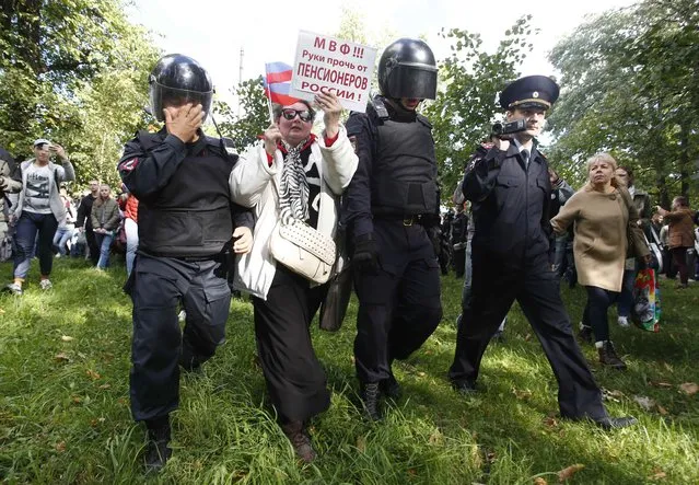 Policemen, affected by tear gas, attempt to detain a protester during a rally against pension reforms, which envisage raising the retirement age of Russian citizens, in St. Petersburg, Russia September 16, 2018. (Photo by Anton Vaganov/Reuters)