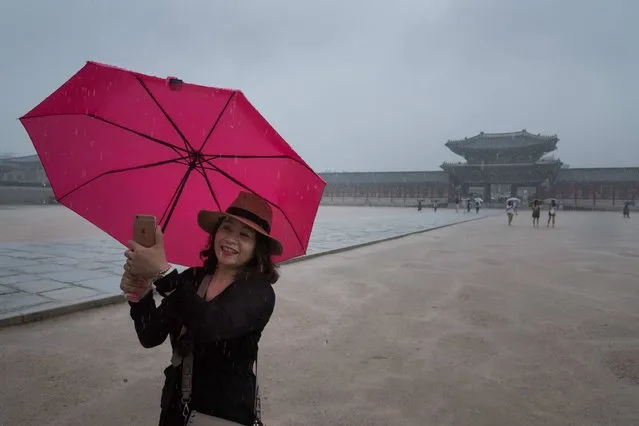 A woman takes a photo before Gyeongbokgung palace in Seoul on July 10, 2017. South Korea is experciencing its annual rainy season, which typically lasts from late June to late July. (Photo by Ed Jones/AFP Photo)