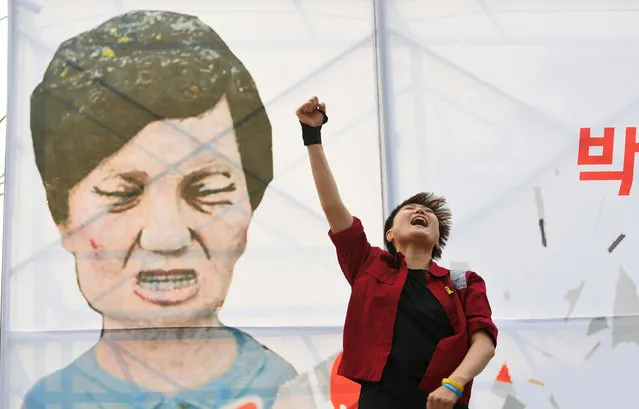 A protester shouts slogans in front of a caricature of South Korea's President Park Geun-Hye during a rally urging the impeachment of the president in Seoul on December 7, 2016. South Korea's scandal-hit Park said on December 6 she would accept the result of a looming and possibly lengthy impeachment process, but defied pressure to resign immediately. (Photo by Jung Yeon-Je/AFP Photo)