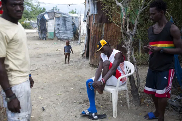 In this August 29, 2018 photo, Changlair Aristide gets ready to play soccer, outside his home by the Truitier landfill in the Cite Soleil slum of Port-au-Prince, Haiti. Changlair, who supports his family by scavenging the landfill, coaches the Truitier soccer team made up mostly of trash collectors like him, who play a summer championship against a team from Cite Soleil. (Photo by Dieu Nalio Chery/AP Photo)