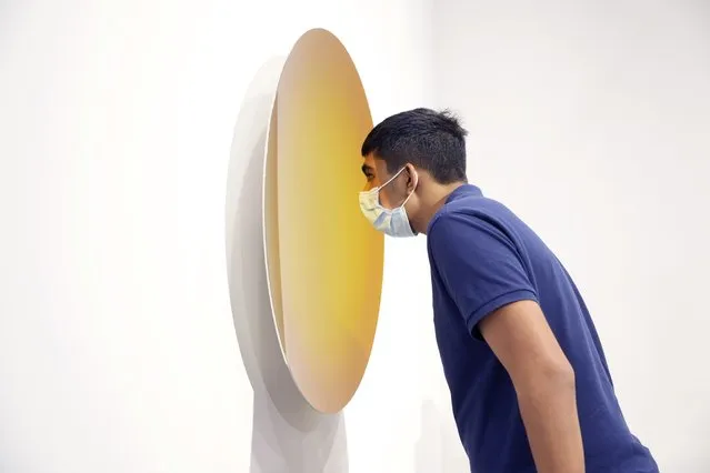 A visitor takes a close look at an artwork titled “Spanish Gold to Pagan Gold” created by British-Indian sculptor Anish Kapoor at Art Basel in Hong Kong Wednesday, May 19, 2021. (Photo by Vincent Yu/AP Photo)