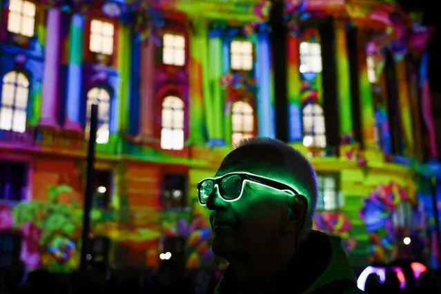 A man watches the illumination at the Faculty of Law at Humboldt University during the Festival of Lights, in Berlin, Germany on October 6, 2023. (Photo by Fabrizio Bensch/Reuters)