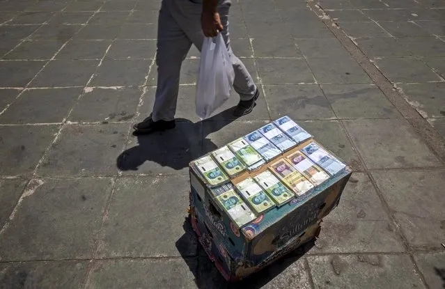 An Iranian man walks past Iranian banknotes displayed on a street in downtown Tehran on June 15, 2021. Iran holds a presidential election on June 18, with ultraconservative Ebrahim Raisi, who heads the judiciary, most likely to win from the seven candidates. (Photo by Morteza Nikoubazl/AFP Photo)