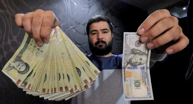 A money changer poses for the camera with a U.S dollar (R) and the amount being given when converting it into Iranian rials (L), at a currency exchange shop in Tehran's business district, Iran, in this January 20, 2016 file photo. Iranian banks will have to adjust to tougher international regulations and may need to offload non-performing loans into a “bad bank” to pick up where they left off when sanctions were imposed almost four years ago. (Photo by Raheb Homavandi/Reuters/TIMA)